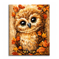 A paint by numbers canvas of a wide-eyed baby owl with fluffy golden-brown feathers nestled among orange autumn leaves.