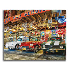 A detailed paint by numbers scene of three classic American cars, a white coupe, a red convertible, and a green muscle car with white stripes, parked in a vintage garage packed with Route 66 road signs, neon advertising, and retro memorabilia.