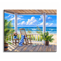 On a beach porch, a wooden rocking chair with a striped throw faces the ocean between potted palms in a paint by numbers design.