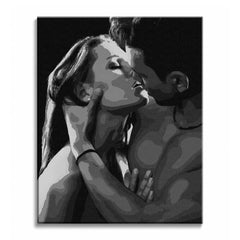 Soft light falls across a kissing couple in a black and white paint by numbers design, with closed eyes, touching lips, a hand at the chest, and a deep black background.