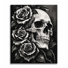 Pale light falls across a cracked skull and a stack of full roses with thorned stems, in a skull and roses paint by numbers design of bone white, charcoal and black.